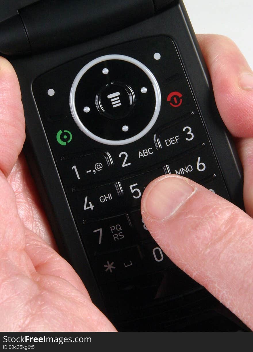 Hand holding mobile telephone with finger touching key. Hand holding mobile telephone with finger touching key