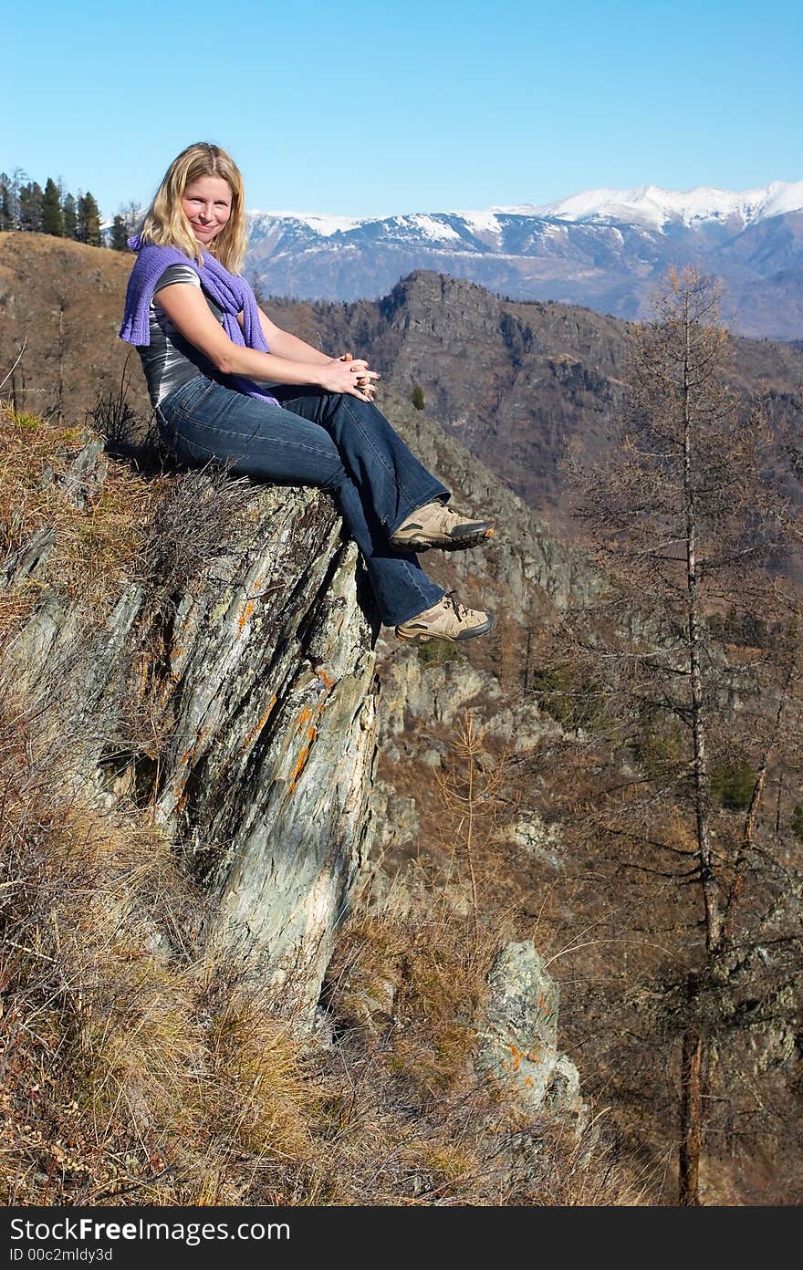 The women sits on a stone.