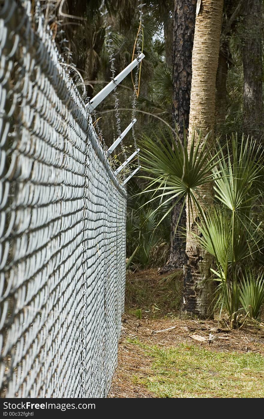A chain-link fence with barbed wire on top. A chain-link fence with barbed wire on top.