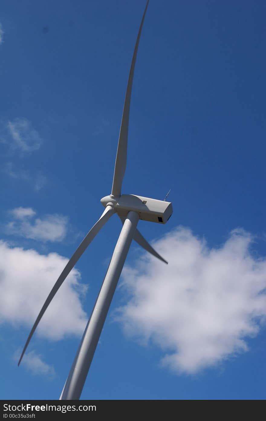 Wind trubine close up with blue sky and white clouds