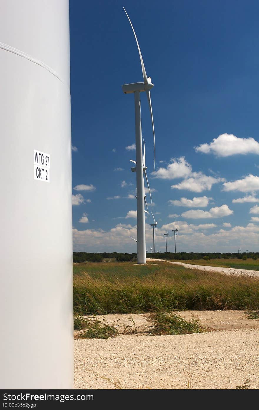 Wind trubines in a field with blue sky and white clouds