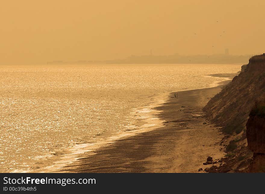 Man and woman in the distance on a quiet beach. Sepia Toned