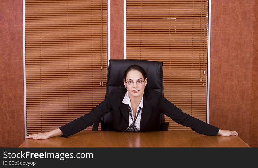 Brunette business woman with black suit holding on to boardroom table. Brunette business woman with black suit holding on to boardroom table