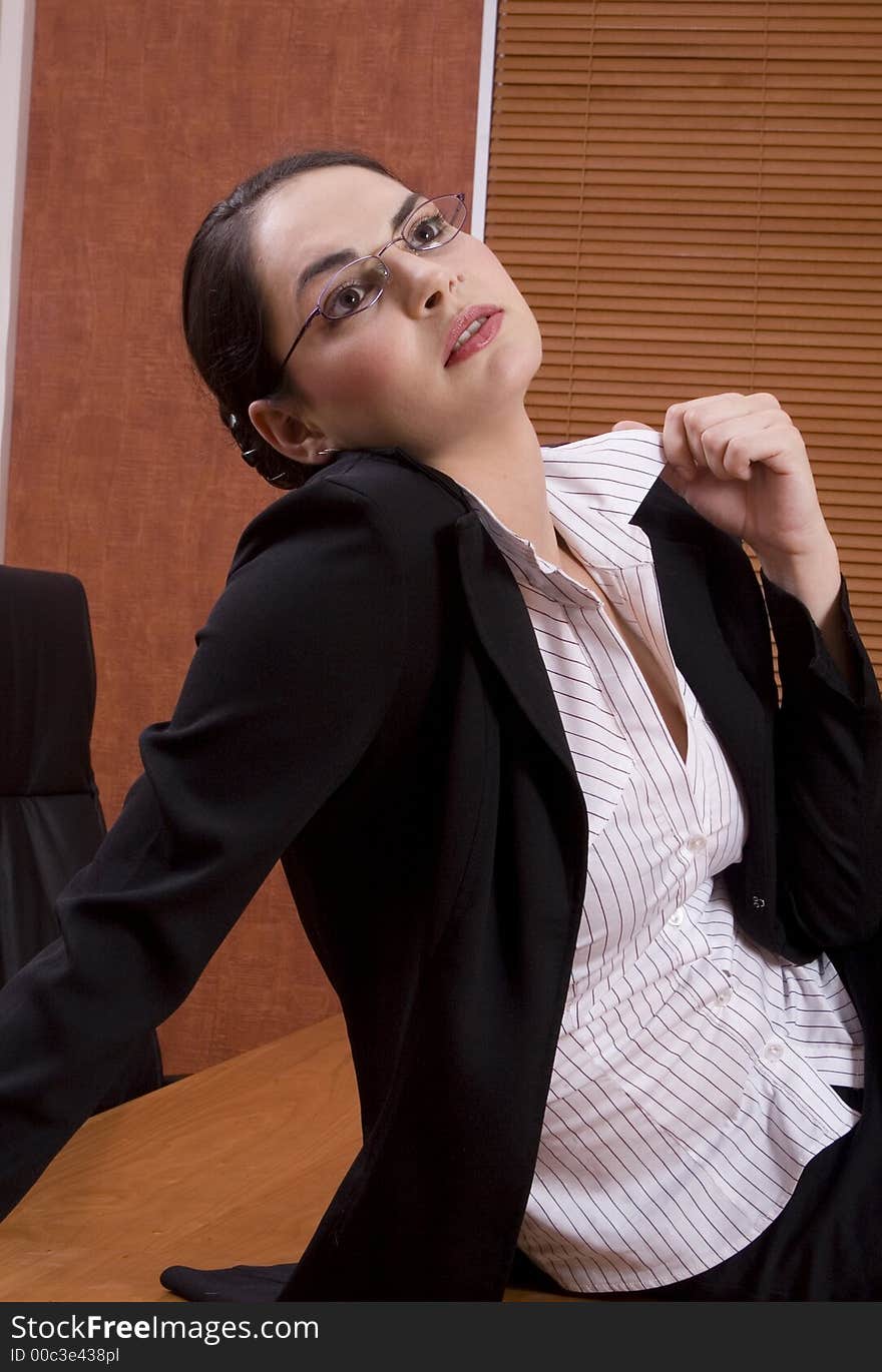 Brunette business woman with black suit looking up and holding shirt. Brunette business woman with black suit looking up and holding shirt