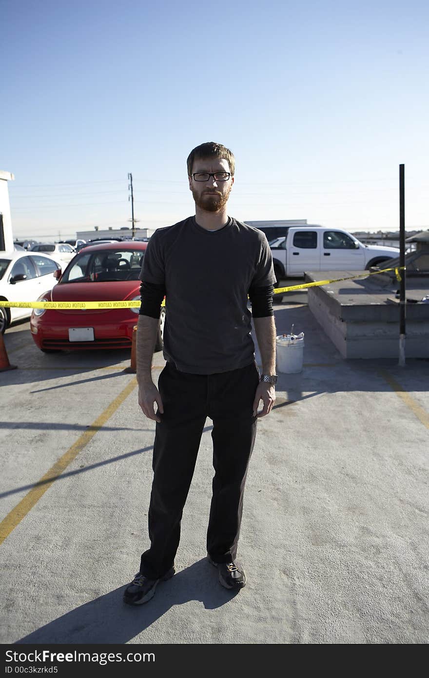 Man wearing tee shirt standing roof top parking lot with cars in the background. Man wearing tee shirt standing roof top parking lot with cars in the background.