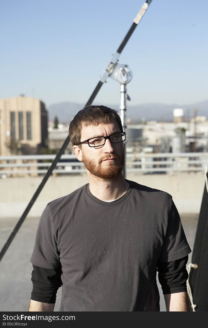 Man wearing tee shirt standing in the sun roof with city in the background. Man wearing tee shirt standing in the sun roof with city in the background.