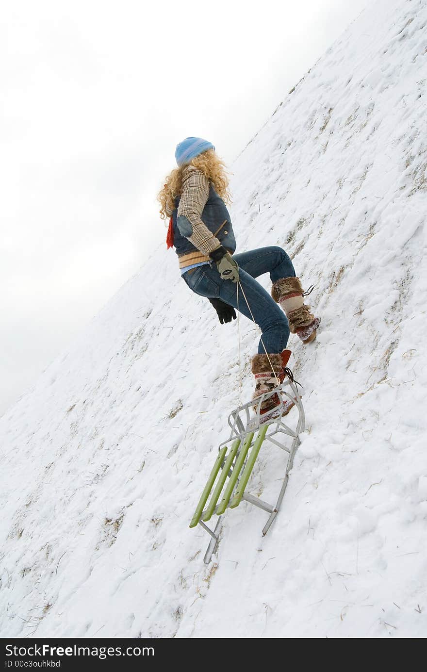 Beautiful young girl climbing up with sledge on the rope. Beautiful young girl climbing up with sledge on the rope