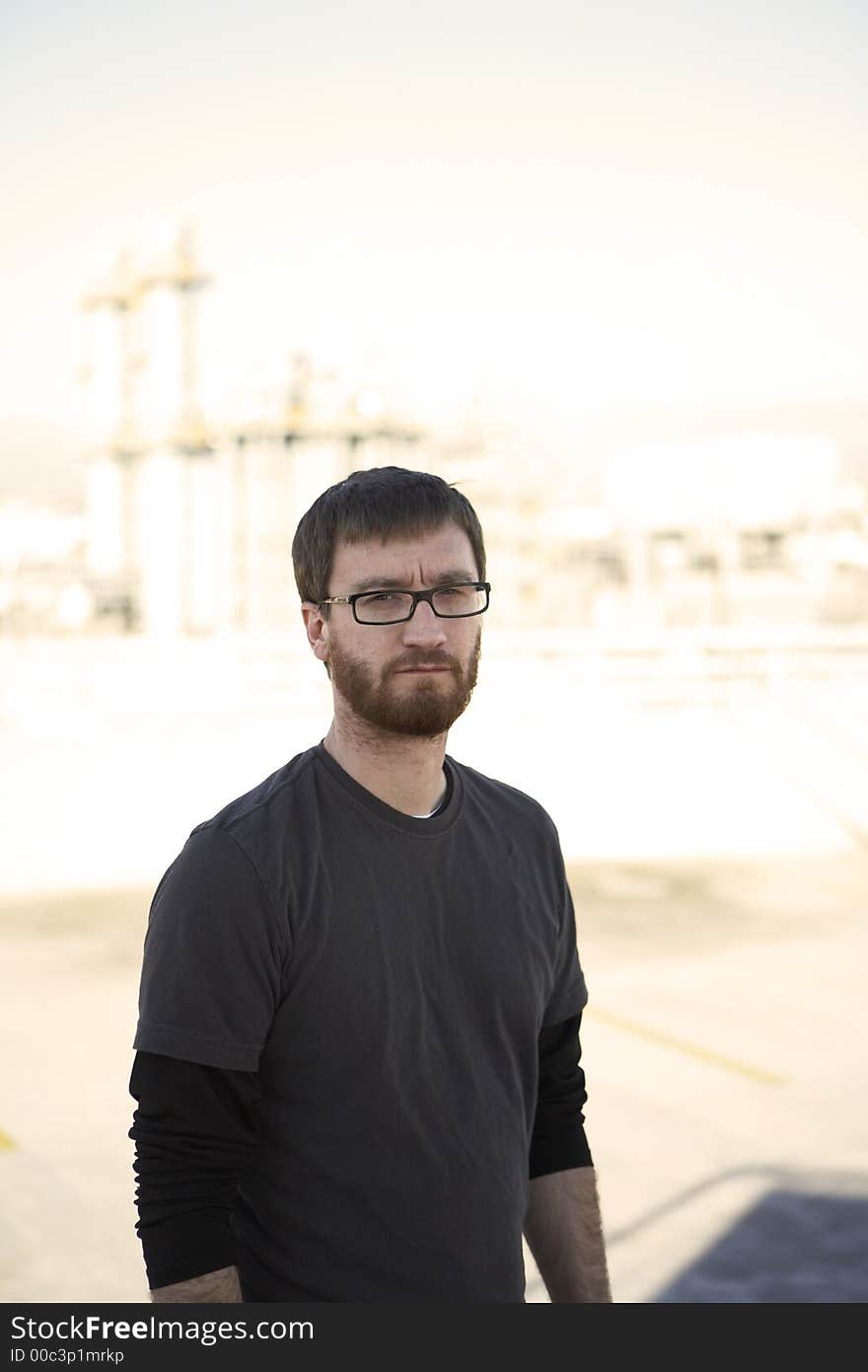 Man wearing tee shirt standing on the roof with city in the background. Man wearing tee shirt standing on the roof with city in the background.