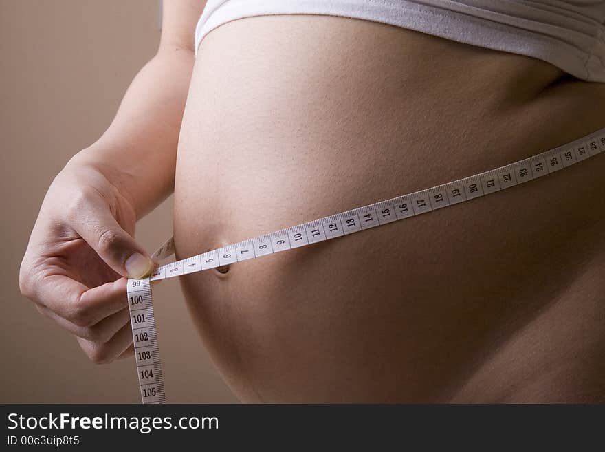 Pregnant woman measuring her belly while standing. Pregnant woman measuring her belly while standing