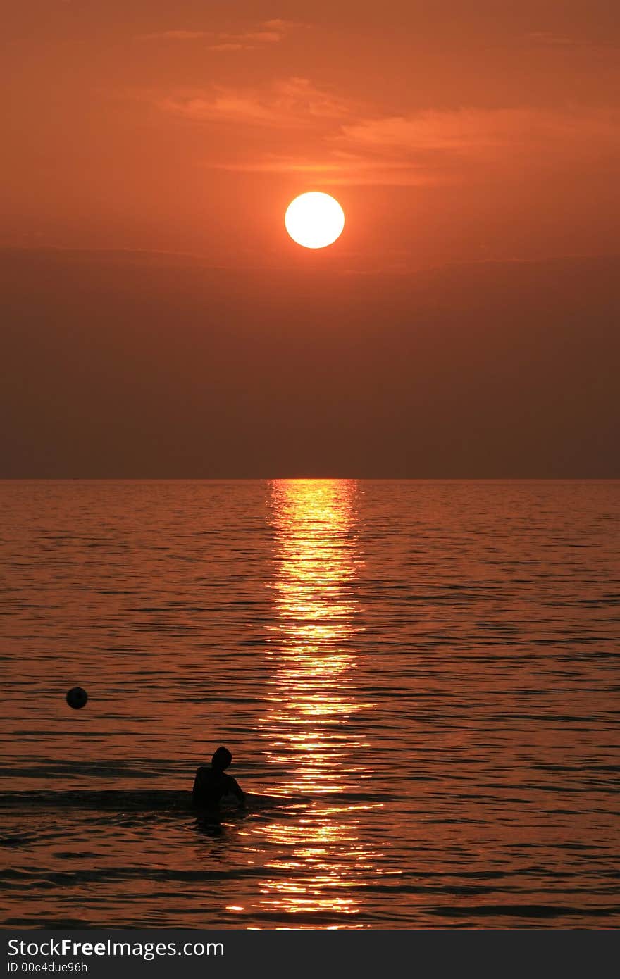 A boy throwing a ball in background of a beautiful sunset. A boy throwing a ball in background of a beautiful sunset