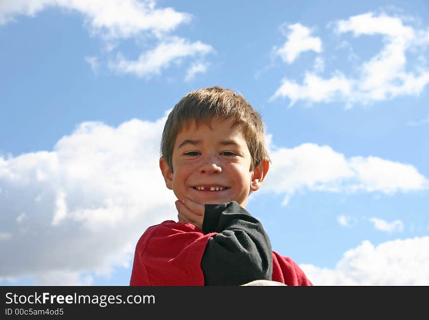 Boy smiling with the clouds in the background. Boy smiling with the clouds in the background