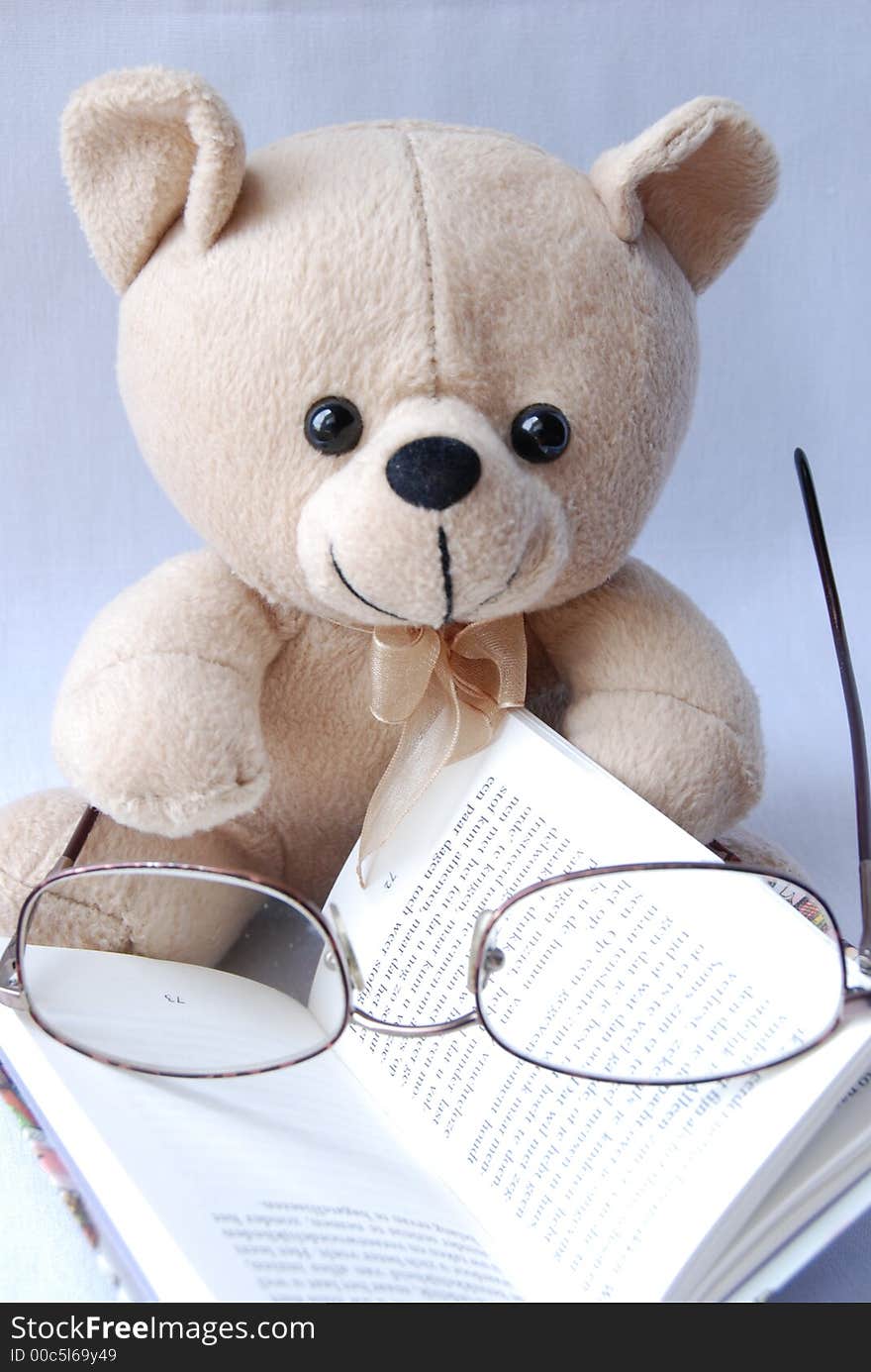 A cute little bear with glasses, reading a book. A cute little bear with glasses, reading a book