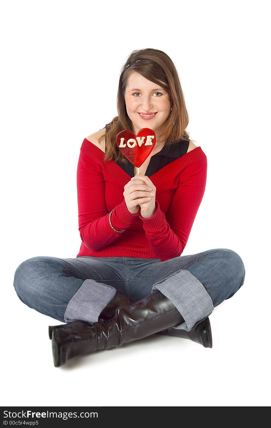 Sitting girl holding a big red 'love' lollipop. Isolated on white. Sitting girl holding a big red 'love' lollipop. Isolated on white.