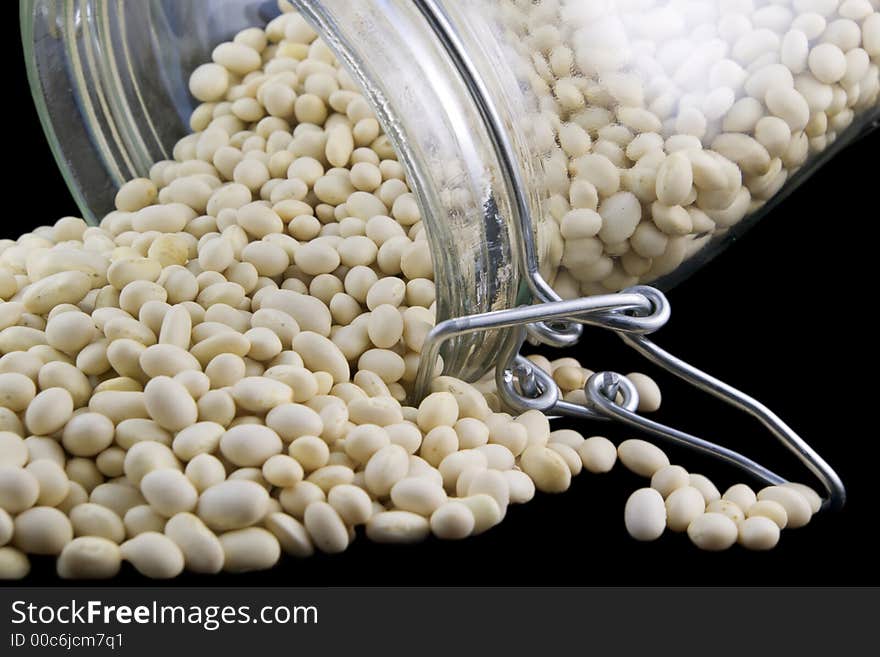 White kidney beans in a pile near open glass jar. White kidney beans in a pile near open glass jar