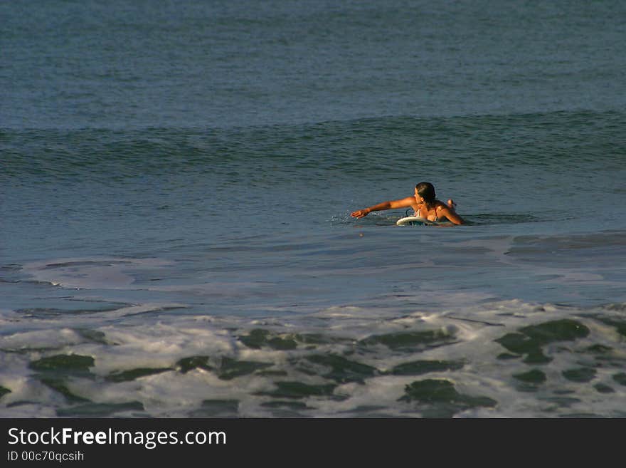 A woman paddles to catch an oncoming wave while surfing in Puerto Viejo, Costa Rica. A woman paddles to catch an oncoming wave while surfing in Puerto Viejo, Costa Rica.