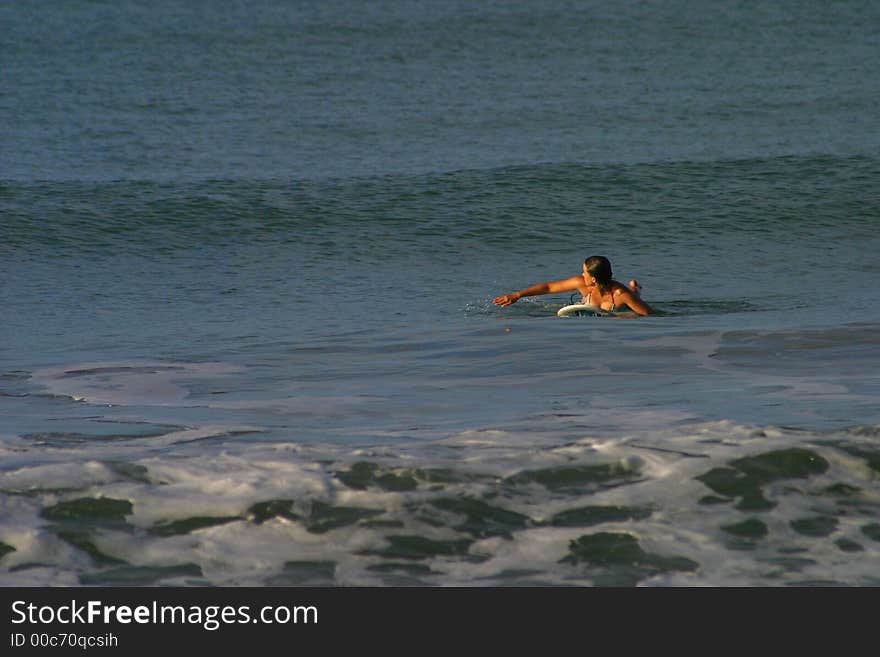 Woman Paddling to Catch a Wave While Surfing