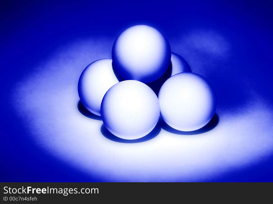 Four white balls for table tennis built a pyramid and illuminated from beneath blue light