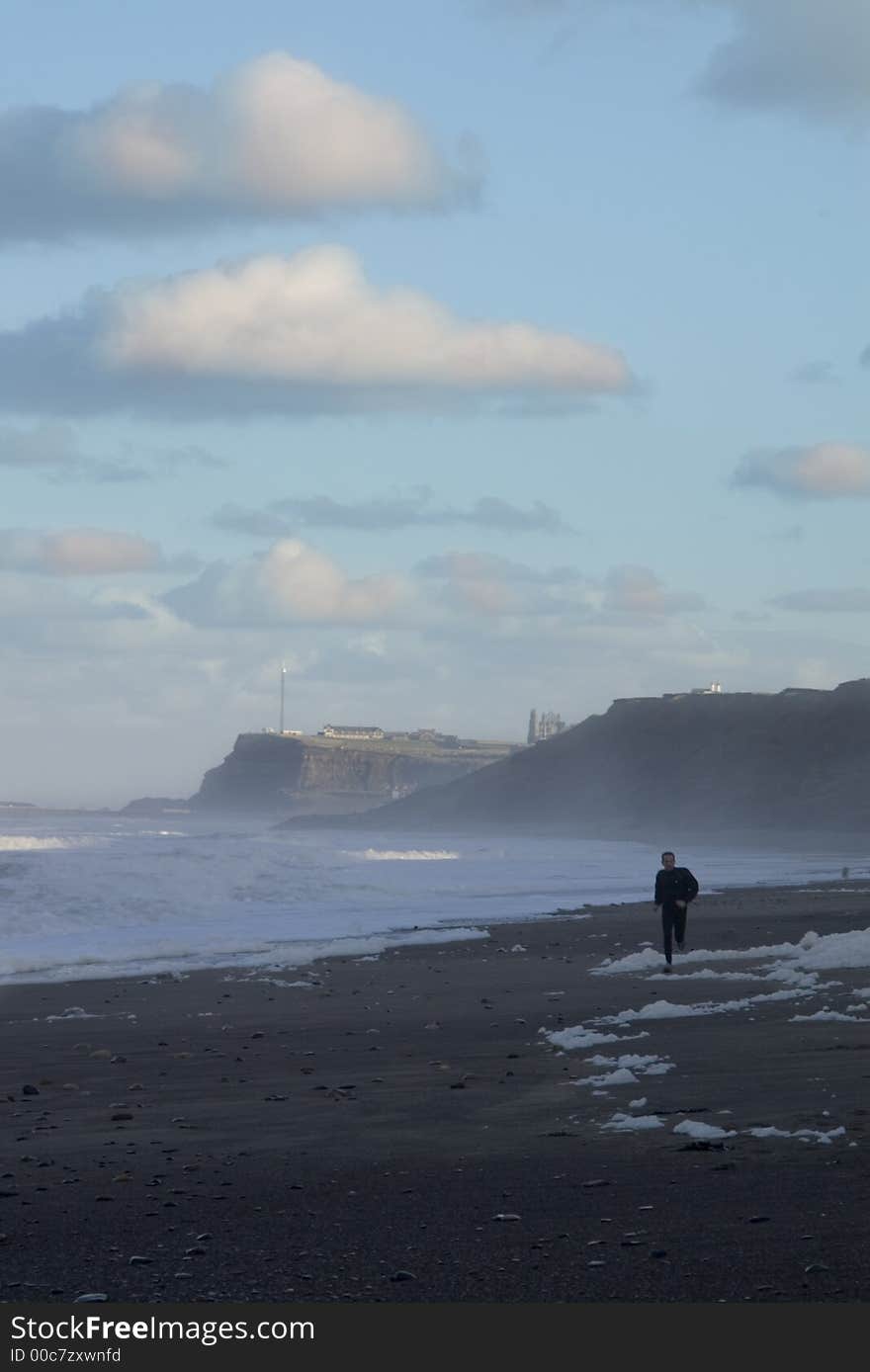 A jogger running on a strech of beach during a storm on the north coast of England. A jogger running on a strech of beach during a storm on the north coast of England.