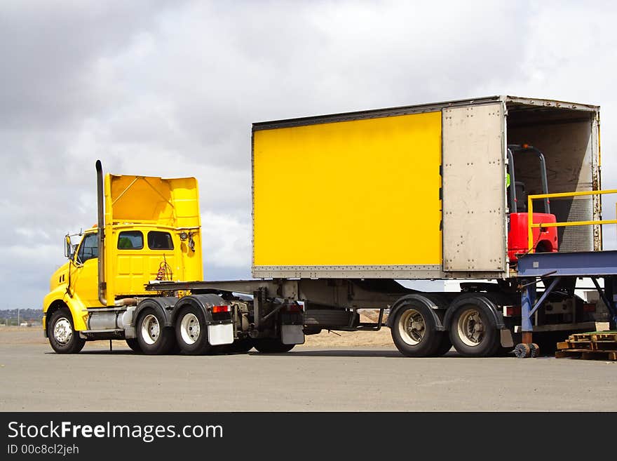 Semi truck on loading dock with forklift