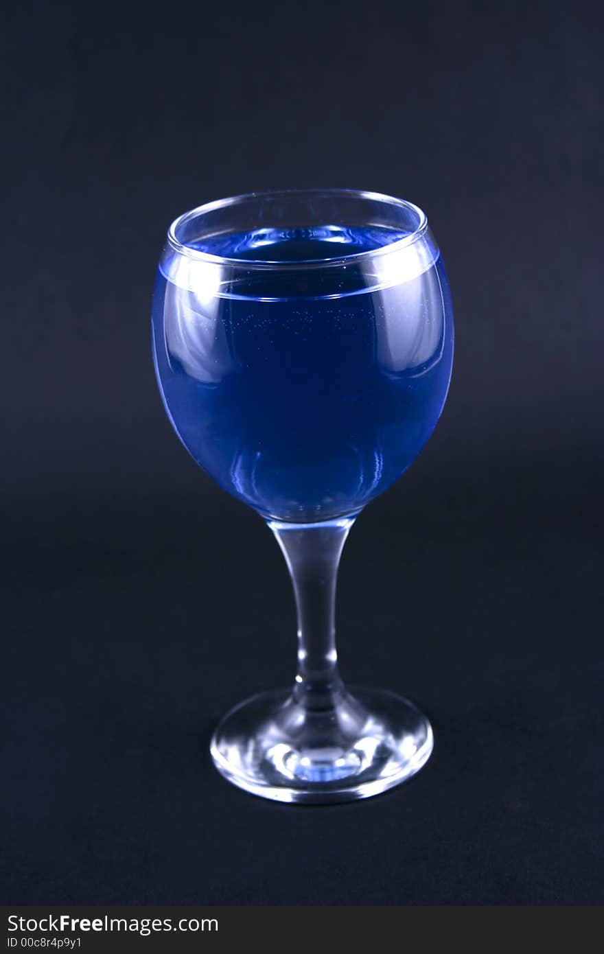 Glass with a blue drink on a black background