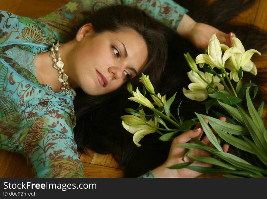 The girl lays on a floor, the sight is inverted to a bouquet from lilies. The girl lays on a floor, the sight is inverted to a bouquet from lilies
