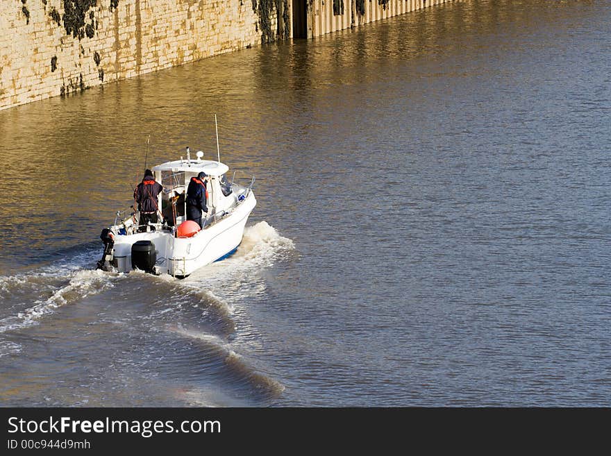 Two fishermen on a small boat head out of a marina. Two fishermen on a small boat head out of a marina