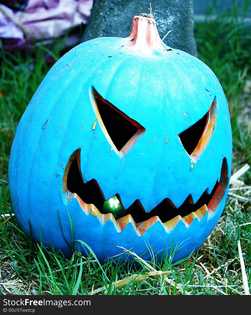 A blue jack-o-latern on grass with a tree behind it. A blue jack-o-latern on grass with a tree behind it.