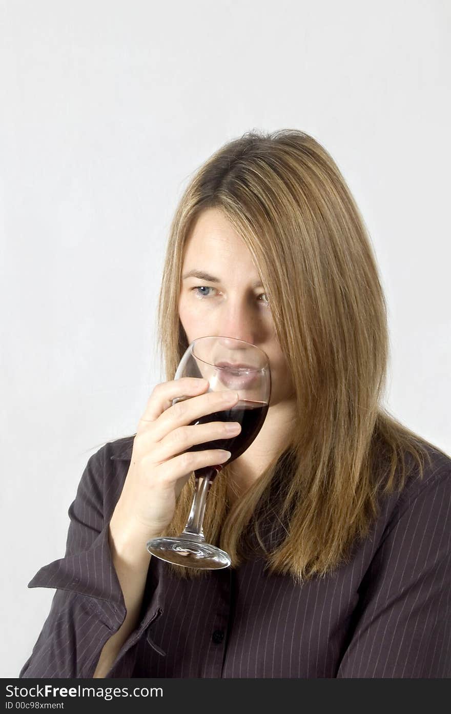 A thoughtful woman drinks a glass of red wine