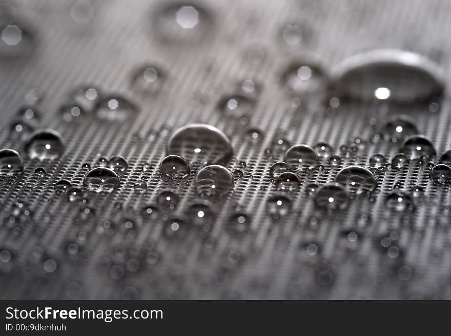 Many beaded up waterdrops on dark textured material creating some interesting reflections. Many beaded up waterdrops on dark textured material creating some interesting reflections.