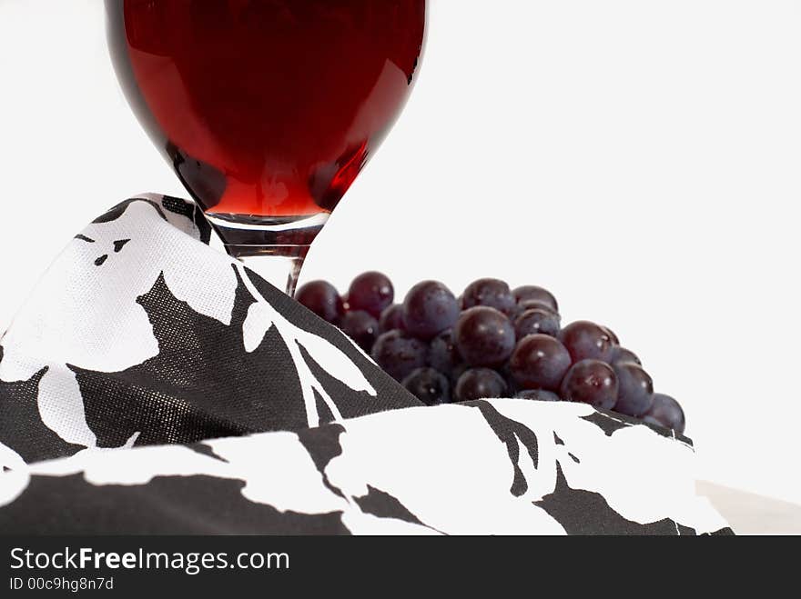 A low view of a wine glass with wine and grapes and napkin