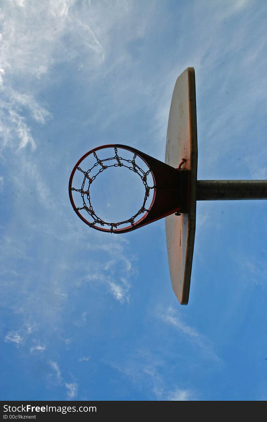 Looking up at blue sky with clouds through basket ball hoop