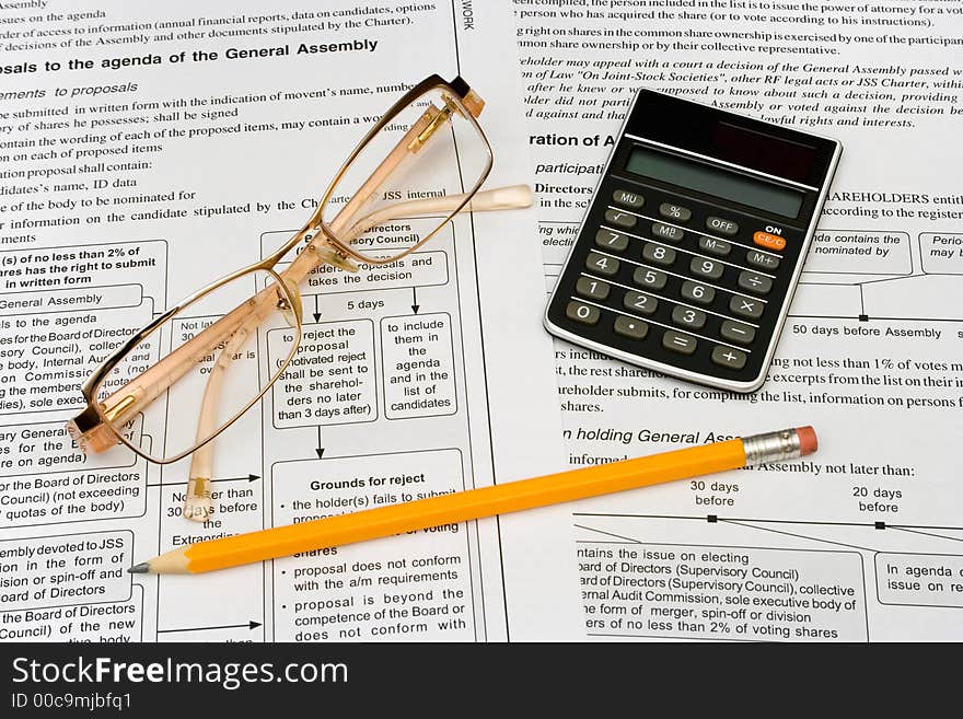 Glasses, pencil and calculator on business background