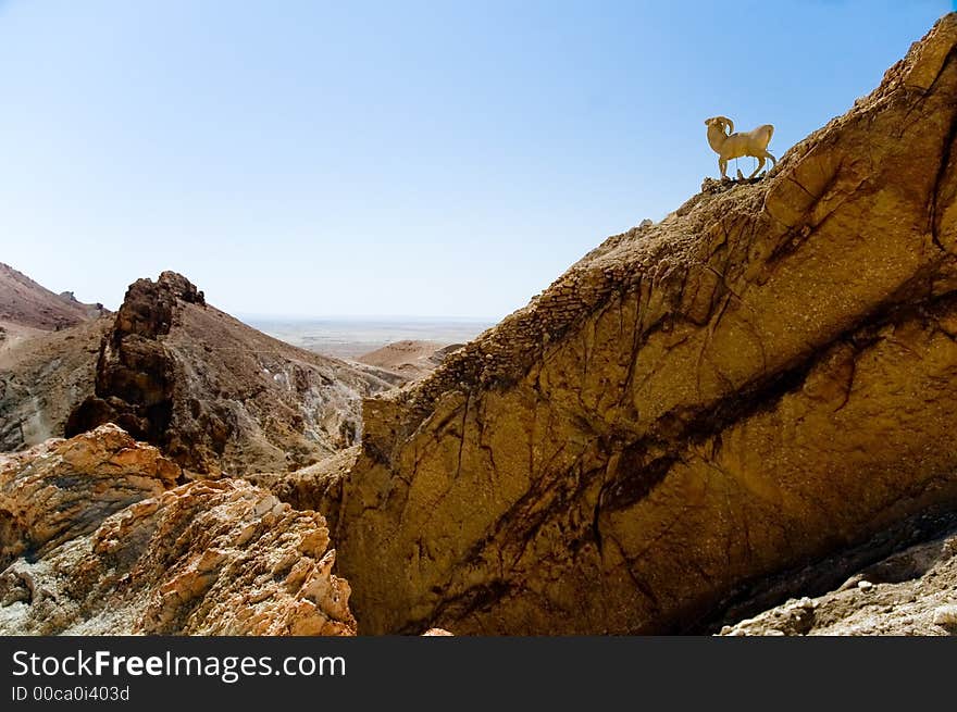 Rocky landscape with stone wild goat watching. Rocky landscape with stone wild goat watching