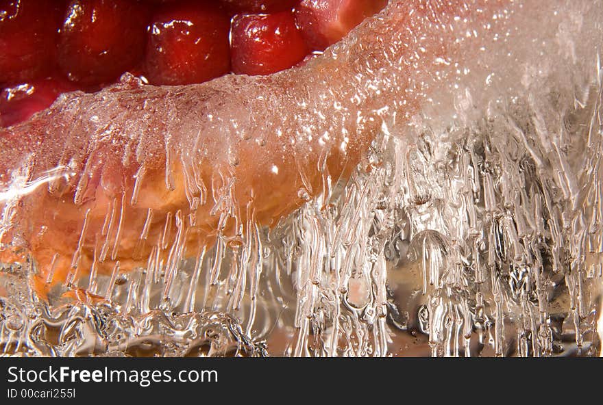 Red pomgranate frozen into a piece of curved ice. Red pomgranate frozen into a piece of curved ice