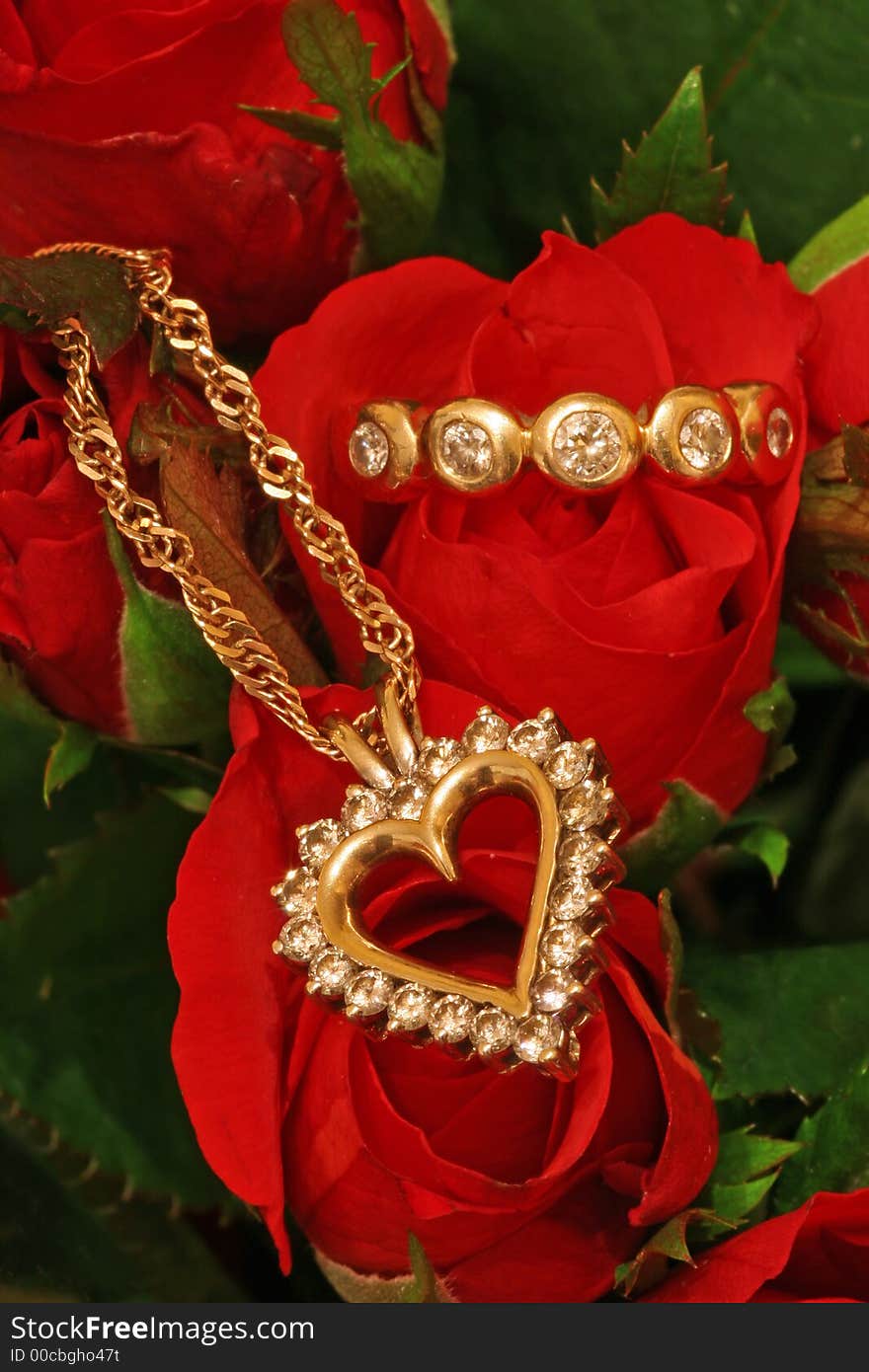 A diamond pendant and a diamond ring on a bunch of red roses. A diamond pendant and a diamond ring on a bunch of red roses