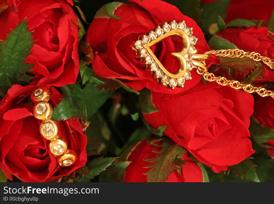 A diamond pendant and a diamond ring on a bunch of red roses. A diamond pendant and a diamond ring on a bunch of red roses