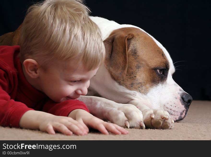 A little boy lays down like her cute puppy, an American Bulldog. A little boy lays down like her cute puppy, an American Bulldog.