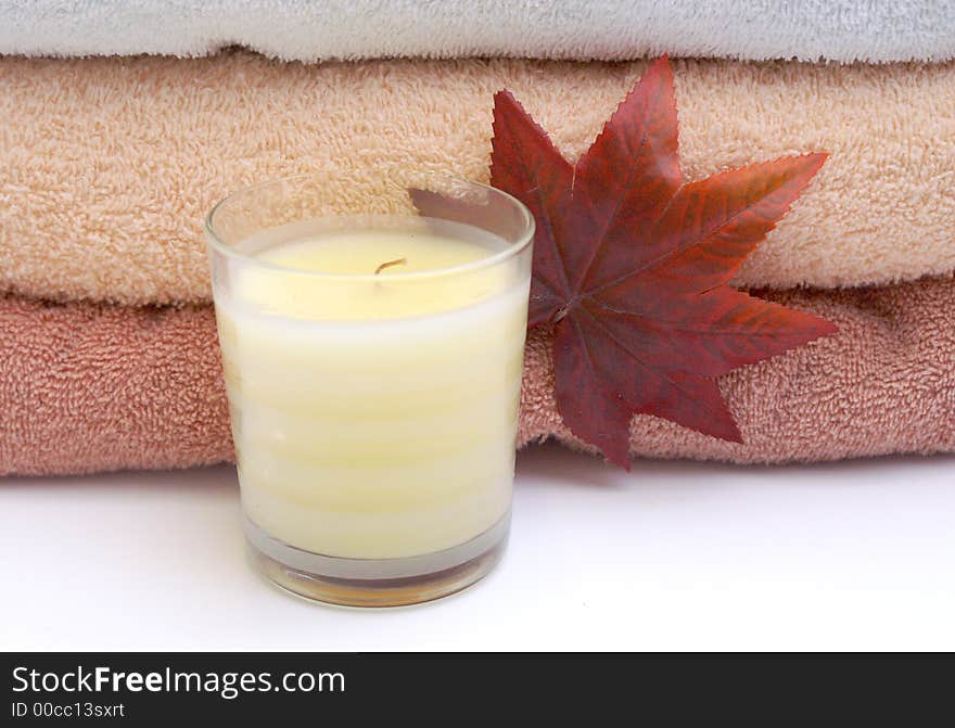 Bathroom relaxation with fall leaf, peach, white and russeyy stacked towels and scented cream candle. Bathroom relaxation with fall leaf, peach, white and russeyy stacked towels and scented cream candle