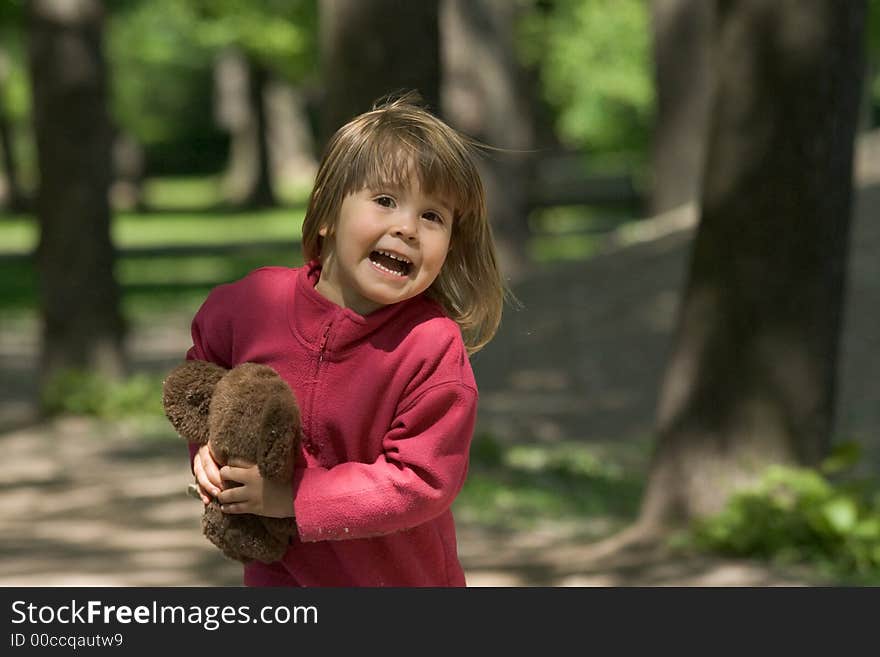 The little girl runs on a wood with a toy in hands. The little girl runs on a wood with a toy in hands