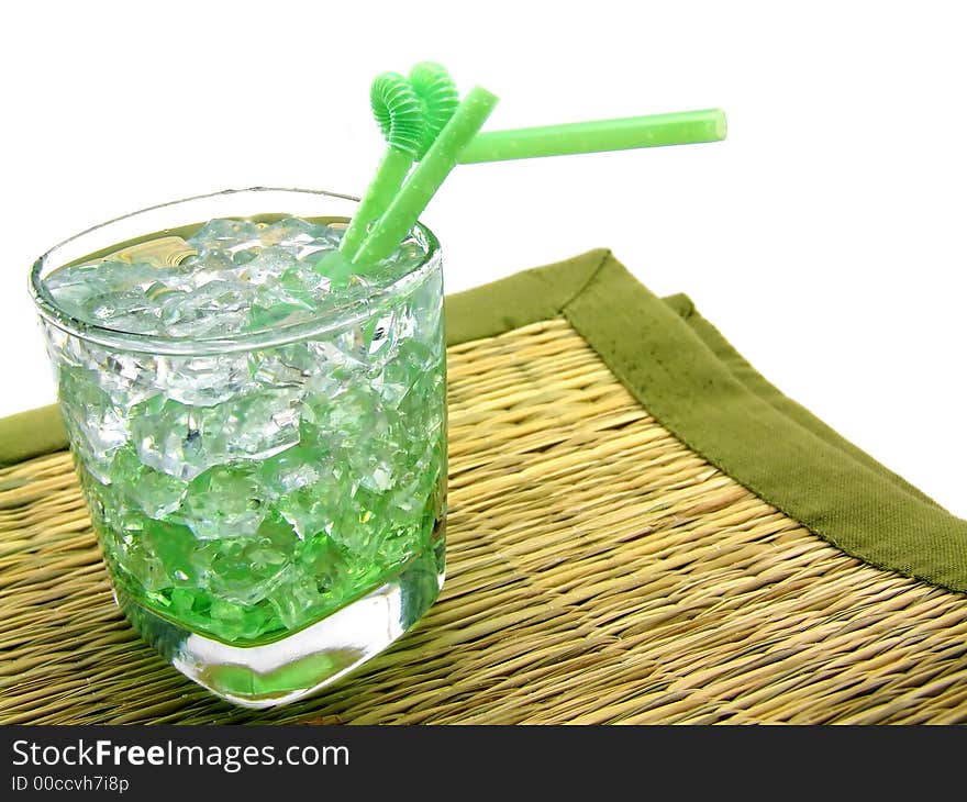 A nice collage of a glass containing a green drink (pisang) on the rocks, standing on a straw underground. A nice collage of a glass containing a green drink (pisang) on the rocks, standing on a straw underground.