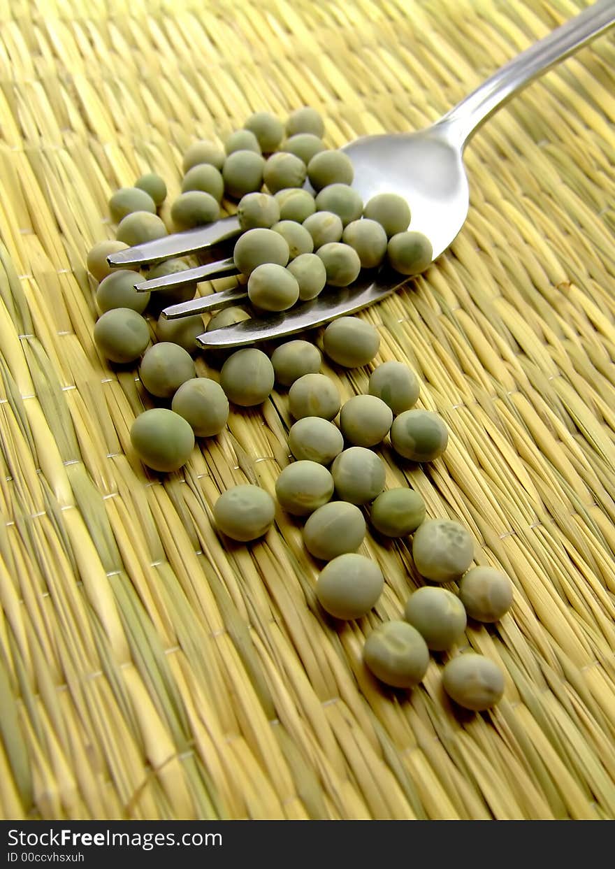 A nice collage of peas and a fork lying on a straw underground. Nice earthly collors. A nice collage of peas and a fork lying on a straw underground. Nice earthly collors