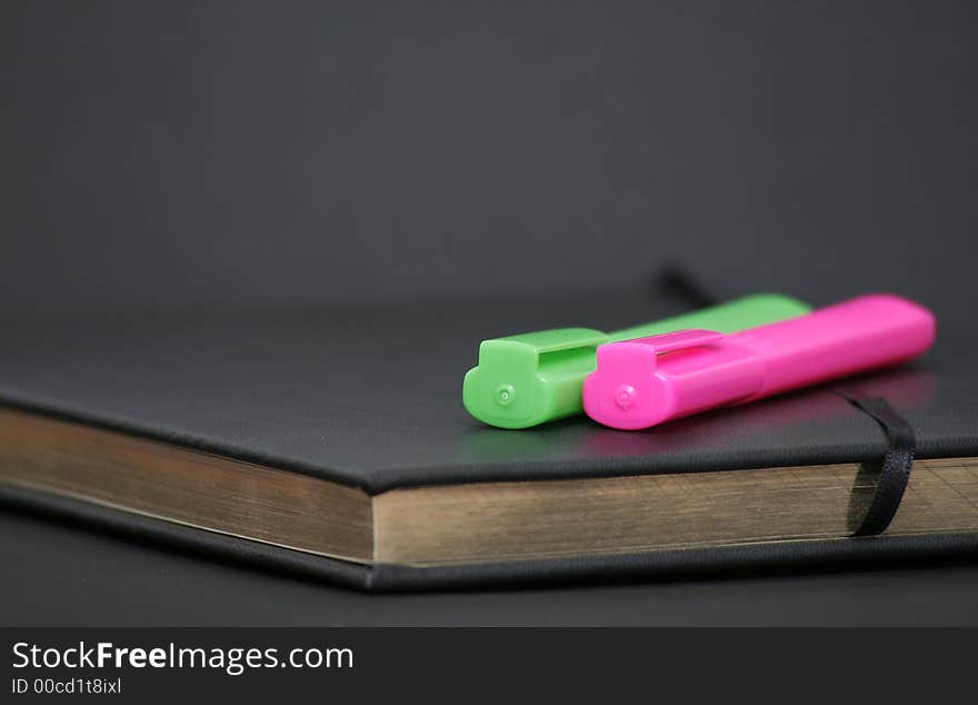 Writing book with golden pages and green and orange markers on top. Writing book with golden pages and green and orange markers on top