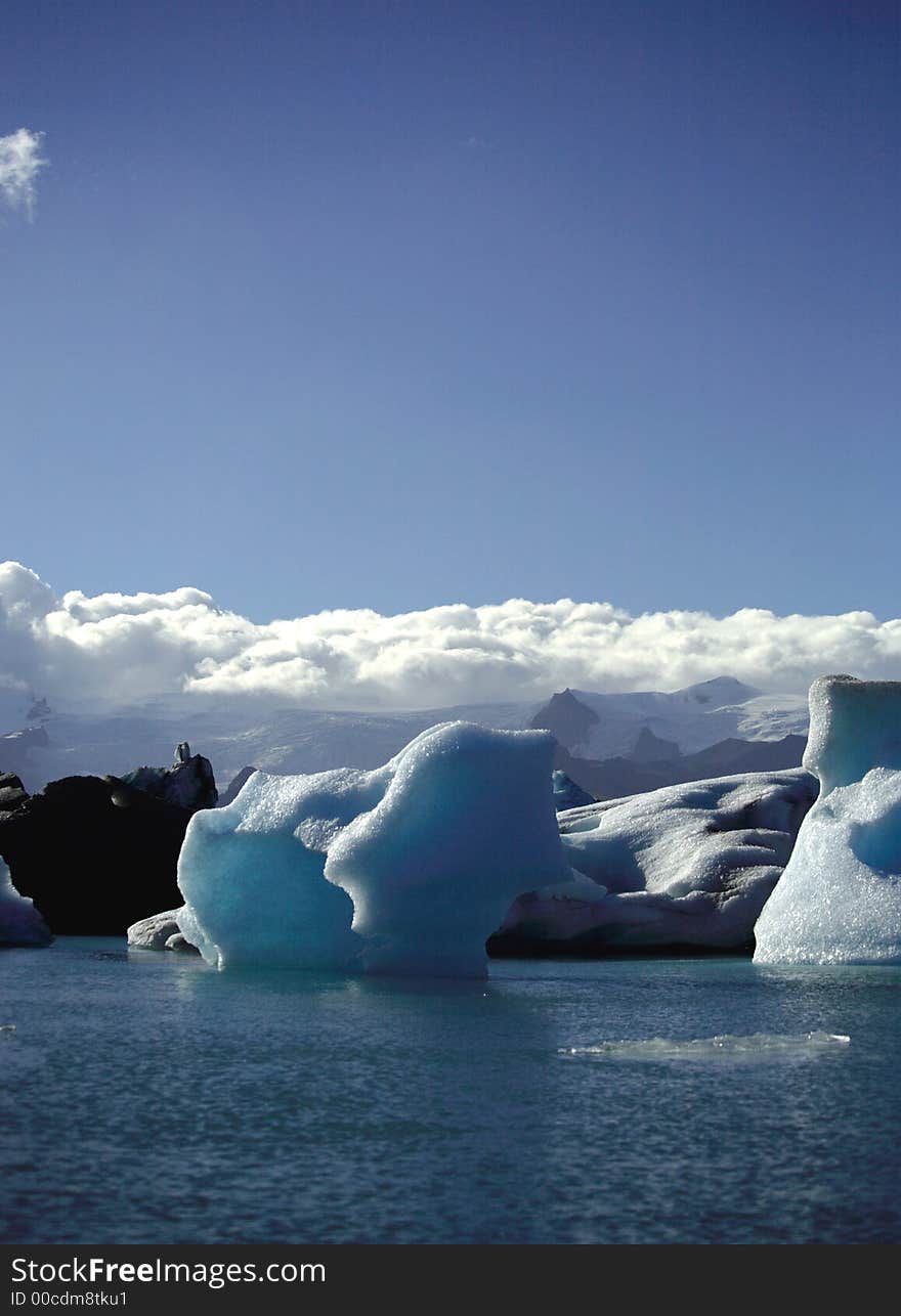 Icebergs against a blue sky and fluffy white clouds. Icebergs against a blue sky and fluffy white clouds