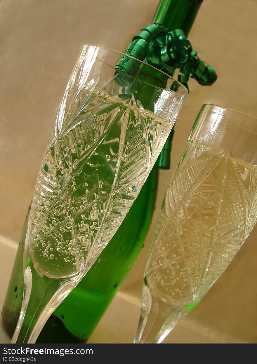 Close-up view of Champagne glasses with bottle on golden background