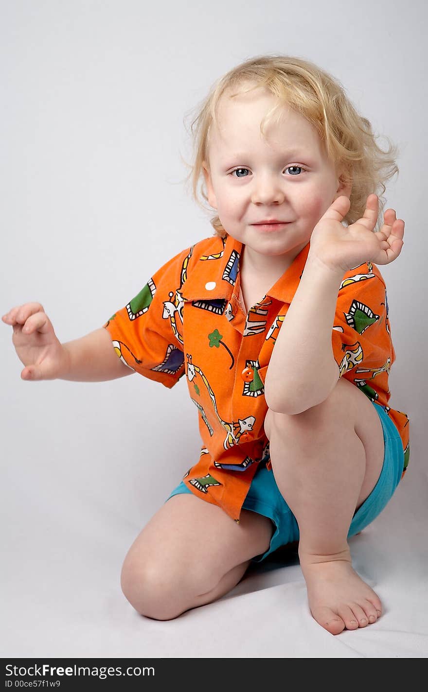 Sitting smiling little boy in orange shirt. Sitting smiling little boy in orange shirt