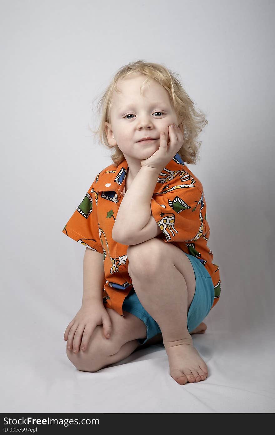 Sitting smiling little boy in orange shirt. Sitting smiling little boy in orange shirt