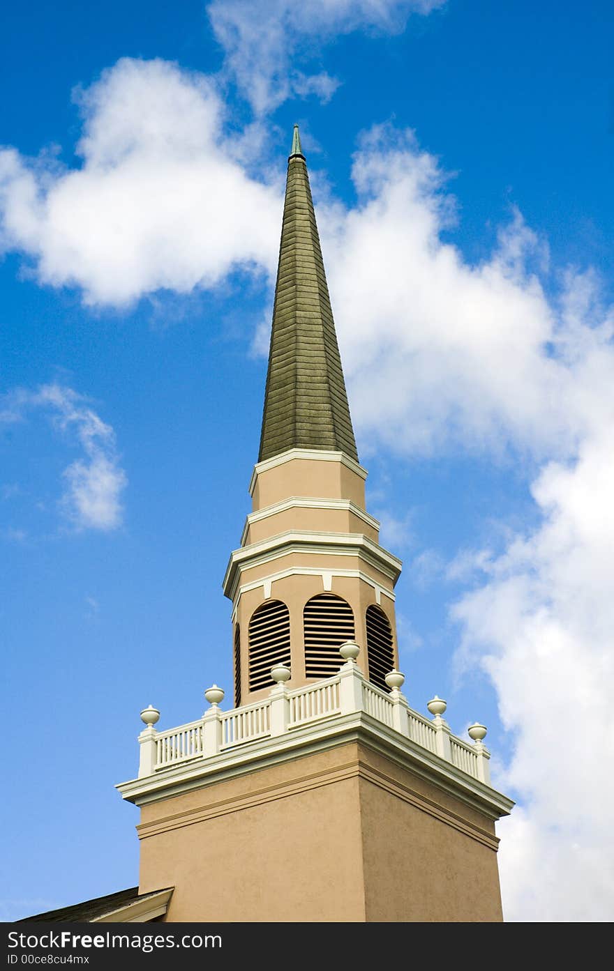 Close up of a small town church steeple against a blue sky with clouds