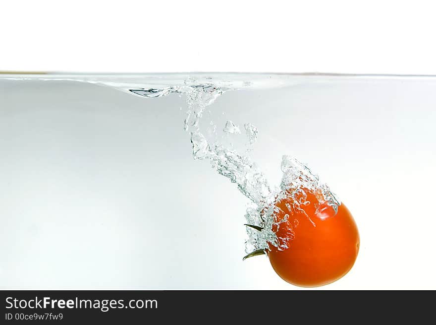 Dropping a tomato in water, isolated on background