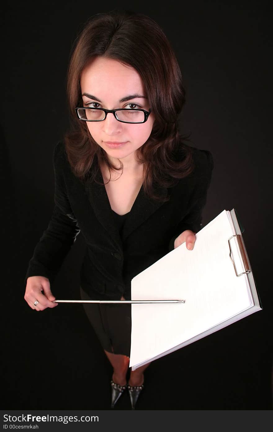 Business woman show with forefinger on a blank paper block notes, black background