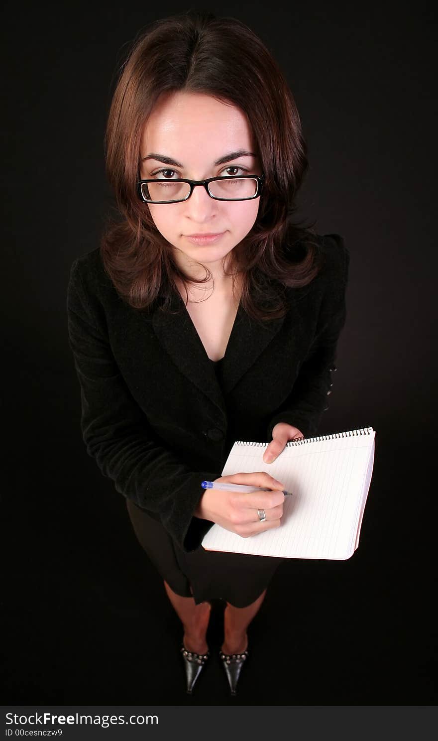 Business woman show with forefinger on a blank paper block notes, black background